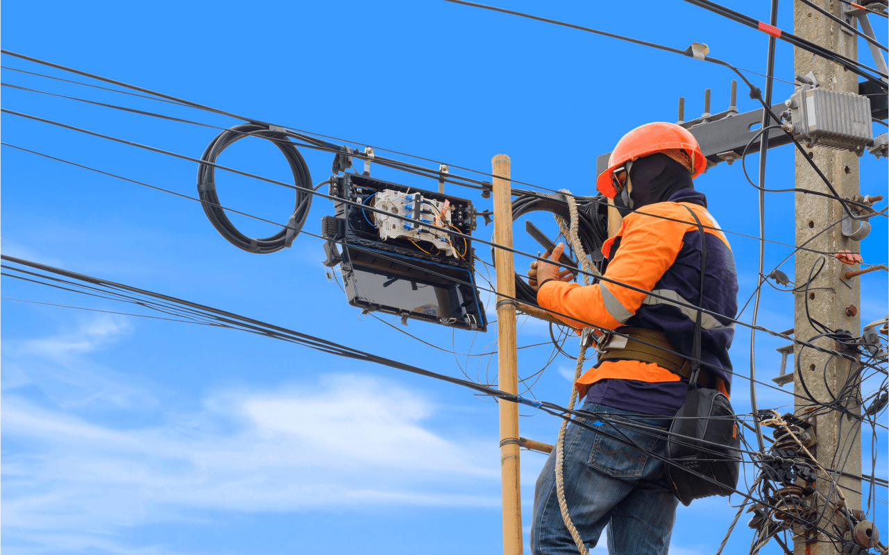 Worker repairing electrical lines on pole.