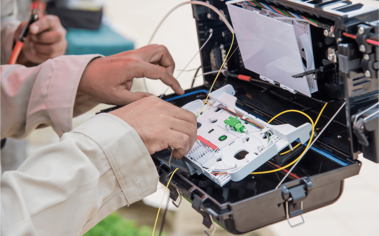 Hands working on fiber optic cables.